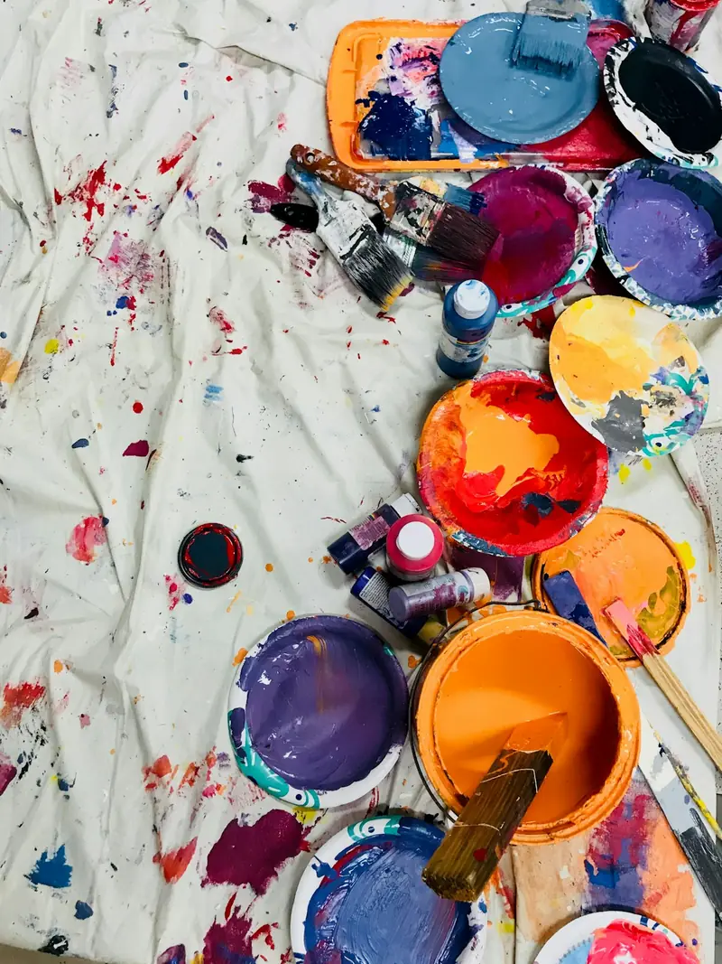 Tarros de pintura de colores sobre una tela manchada de pintura